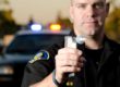 a police officer holds up a breathalyzer device