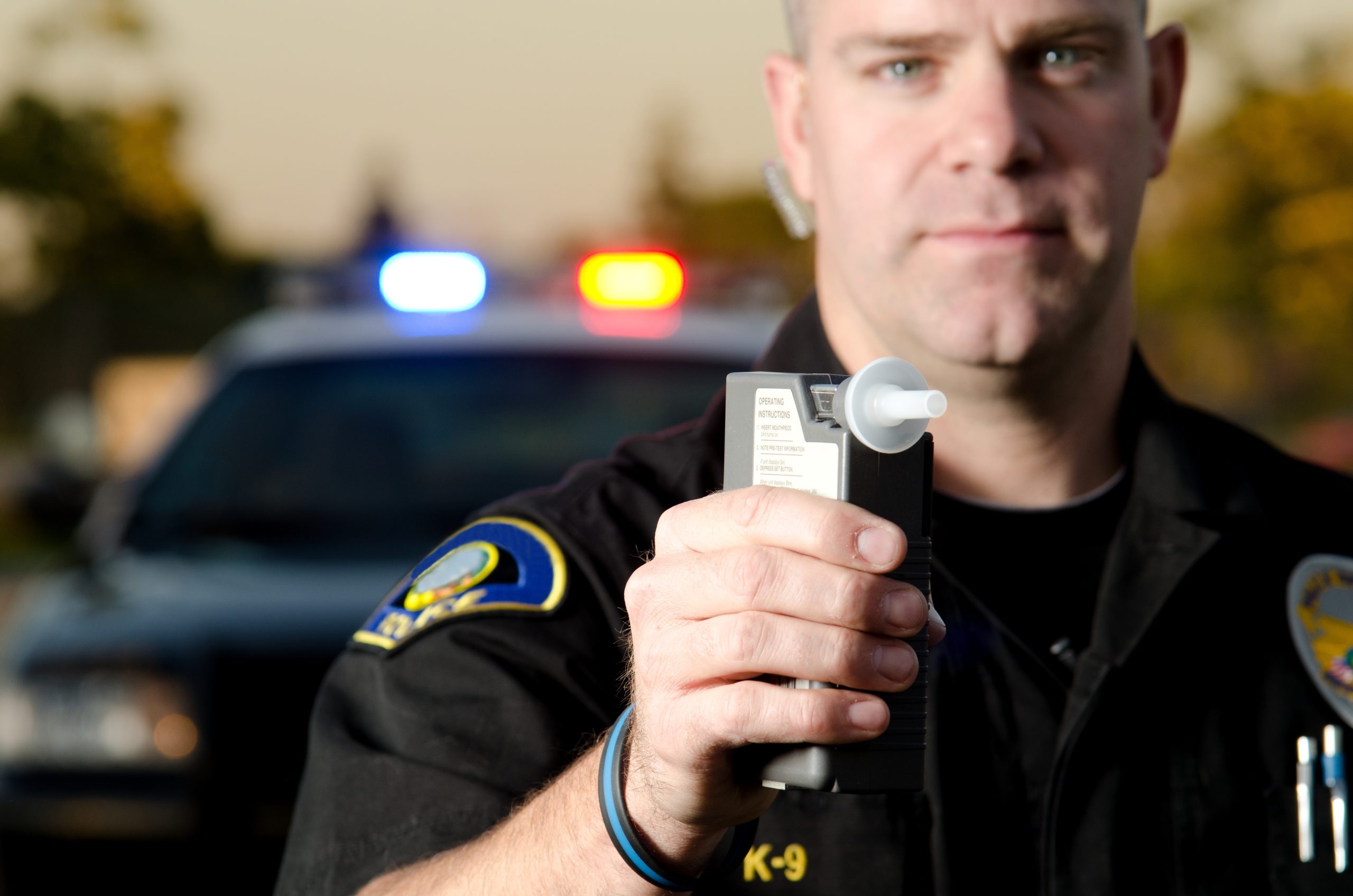 AdobeStock_51711988-scaled a police officer holds up a breathalyzer device