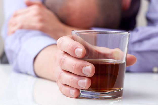 man with head down showing signs of alcoholism