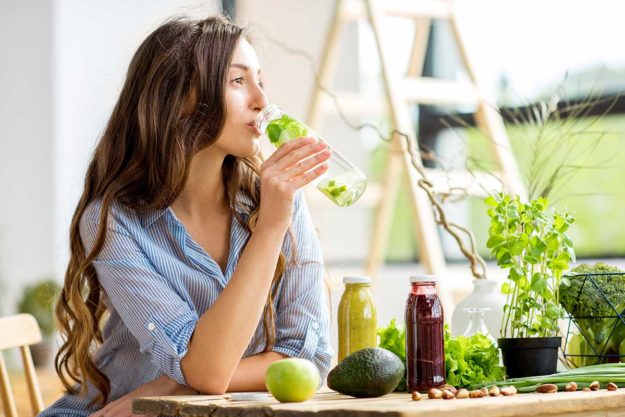 Woman with green healthy food and drinks at home a woman participating in alcohol detox